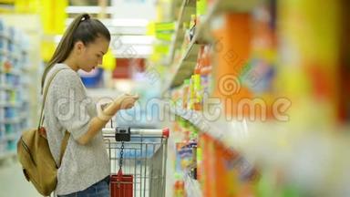 站在货架附近的超市里，长着深色头发和购物车的女人买果汁